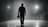 Filmmaker walking away from camera in dimly light studio, holding a camera rig at his waist. Silhouetted by moody backlight. Black, grey, and white tones. Cinematic 8K. Shot on 35mm lens, f/1.8, ISO 100, 1/125 shutter. Clean floor with subtle haze for depth. Low wide angle, rule of thirds. Minimalist luxury feel, soft film grain. Negative space for text. Professional, bold, high-end vibe. 